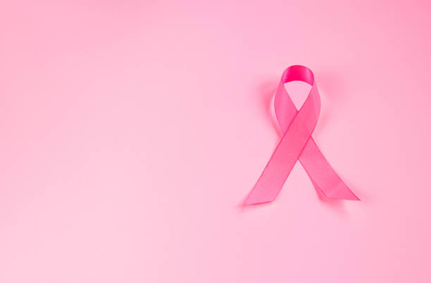 Pink ribbon on colored background. Breast Cancer Awareness Month symbol. Women's health care concept. Promotion of campaign to fight cancer. stock photo