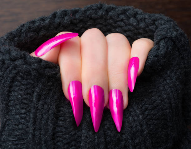 Pink stiletto shaped nails in warm cardigan Woman showing her pink stiletto shaped nails in warm cardigan artificial nail stock pictures, royalty-free photos & images