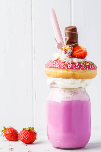 roze aardbei freakshake cocktail met donut en snoep, witte achtergrond. ongezonde desserts concept. - freakshake fruit stockfoto's en -beelden