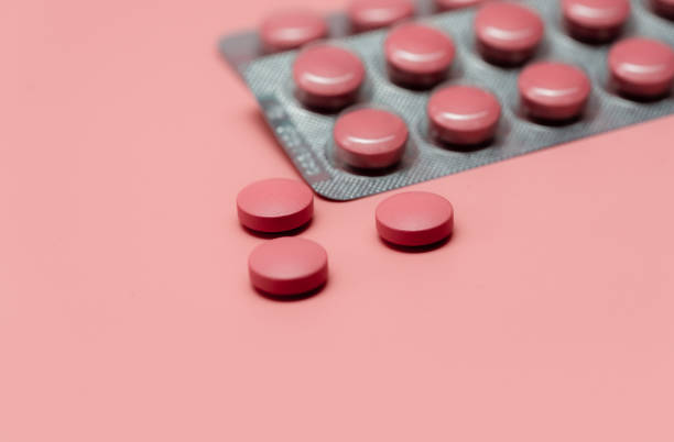 Pink tablets pill on blur blister pack of tablets pills on pink background. Prescription drugs. Woman health concept. Pharmaceutical industry. Online pharmacy banner. Drugs packaging. Treatment dose. stock photo