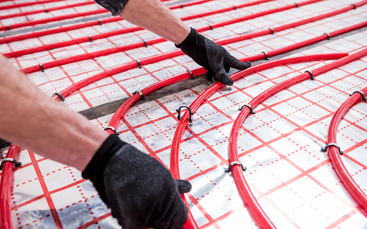 Pipefitter install system of underfloor heating system at home.