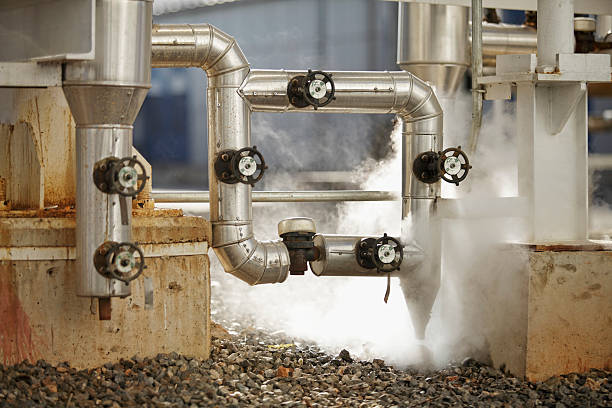 pipelines emitting steam at industrial site stock photo