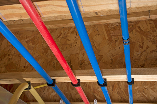 PEX pipes attached to the basement ceiling of a home, angled view.