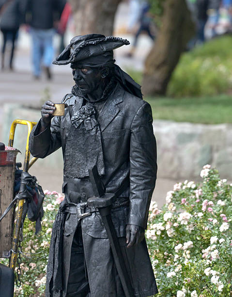 Pirate Street Performer taking a yerba mate break Coyhaique, Chile – February 16, 2016: a street performer takes a mate break in the Pentagonal Plaza of Coyhaique, the capital city of both the Coyhaique province and Aysen Region, Chile.  The pirate holds in his right hand the traditional mate cup with metal straw.   michael stephen wills south america stock pictures, royalty-free photos & images