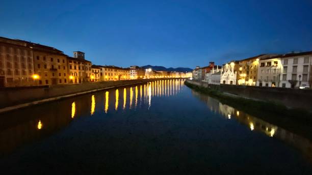 pisa, italy after dark - reflecting street lamps on the calm fiume arno (arno river) stock photo