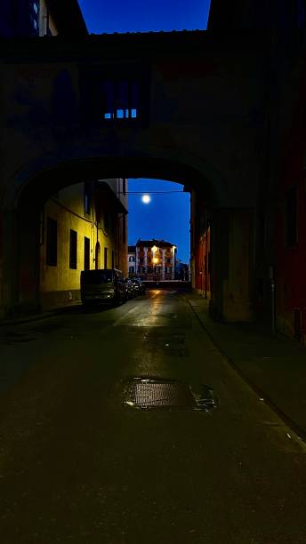 pisa, italy after dark - street lamps and stone archways stock photo