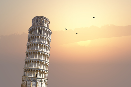 View of historical Pisa Tower in Cathedral Square of Pisa, Italy, on sunrise or sunset sky background.
