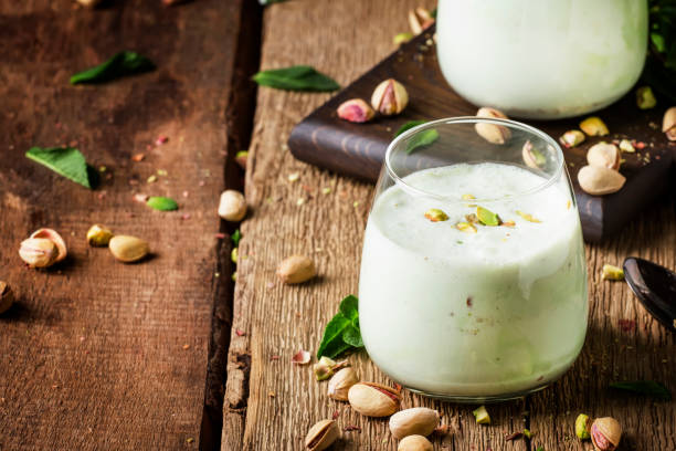Pistachio milk cocktail with ice cream, nut and green mint Pistachio milk cocktail with ice cream, nut and green mint, old wooden background, selective focus pistachio stock pictures, royalty-free photos & images