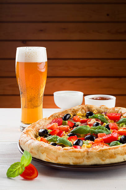 Pizza and glass of beer on wooden table stock photo