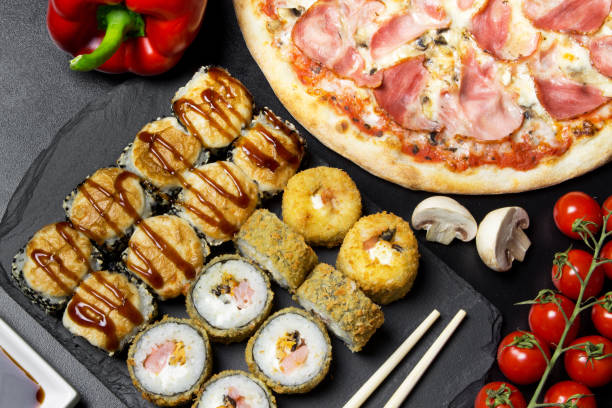 Pizza and sushi rolls tempura and bake rolls on the background of ingredients .Pizza, sushi food photo for menu. Combo set of rolls and pizza. stock photo