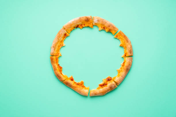 Pizza crust only isolated on a green background. Pizza leftovers top view. Flat lay with pizza pepperoni leftovers on a green-mint background. Pizza crust isolated on a colored background. pastry dough stock pictures, royalty-free photos & images