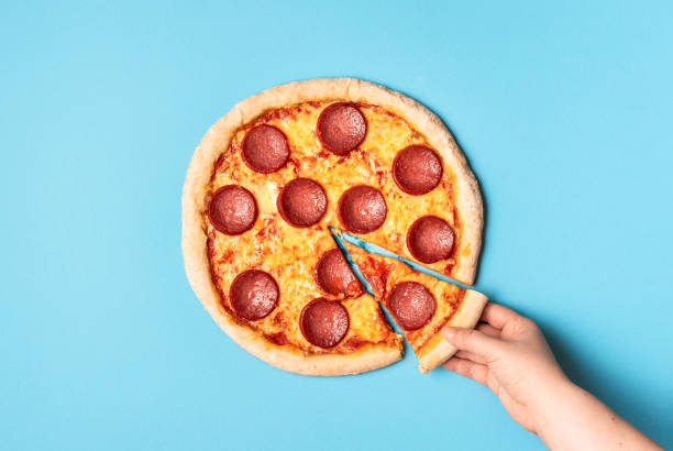 pizza pepperoni et en prenant une tranche de pizza. manger du salami pizza - pizza photos et images de collection