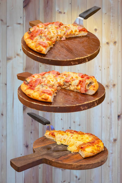 Pizza with ham and cheese on the wooden tray is placed on a wooden background stock photo