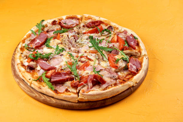Pizza with meat and cheese on yellow background stock photo