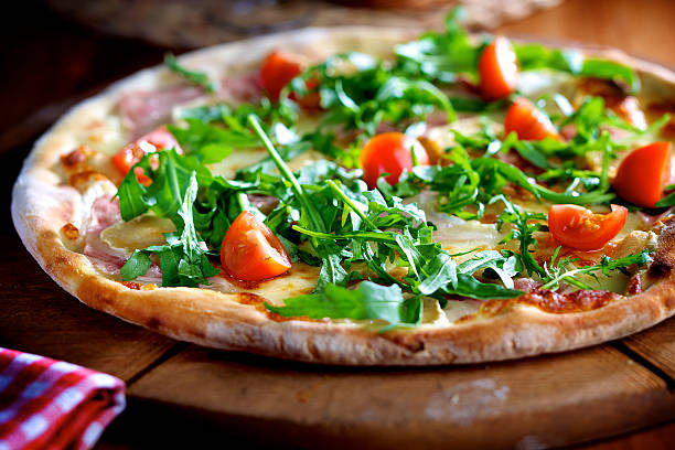 Pizza with rocket salad, ham and cherry tomatoes Fresh and delicious pizza with prosciutto, parmesan, rocket salad and cherry tomatos arugula stock pictures, royalty-free photos & images