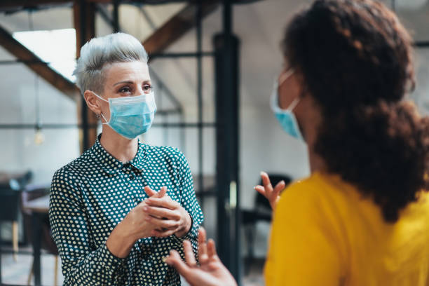 Place of work Colleagues businesswomen in the office talking while wearing medical face mask micro organism photos stock pictures, royalty-free photos & images