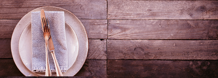 Place setting in vintage pink on old wood. Background for a mother's day dinner. Horizontal top view with space for text.