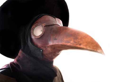 A primitive gas mask in the shape of a bird's beak. A common belief at the time was that the plague was spread by birds. It was thought that by dressing in a bird-like mask, the wearer could draw the plague away from the patient and onto the garment the plague doctor wore. The mask also included red glass eyepieces, which were thought to make the wearer impervious to evil. The beak of the mask was often filled with strongly aromatic herbs and spices to overpower the miasmas or 