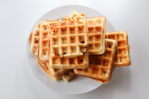 Plain waffles on a while plate against a white background.