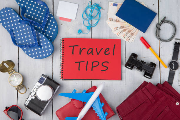 plane, passport, money, camera, compass, note pad with text "Travel tips", binoculars, jeans, watch, flip flops, wallet stock photo