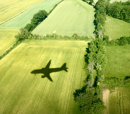 Shadow of a passenger plane in the middle of the fields in spring near Saint-Exupéry airport in Lyon, France
