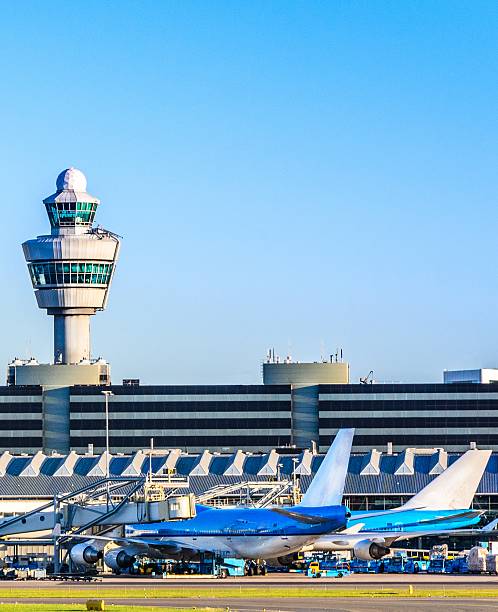 planes waiting at a terminal in an airport - schiphol stockfoto's en -beelden
