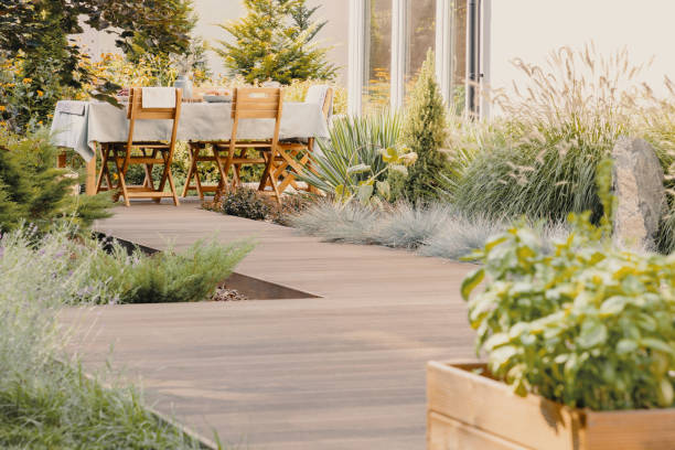 planten en houten stoelen aan tafel met voedsel op het terras van het huis in de zomer - formele tuin stockfoto's en -beelden