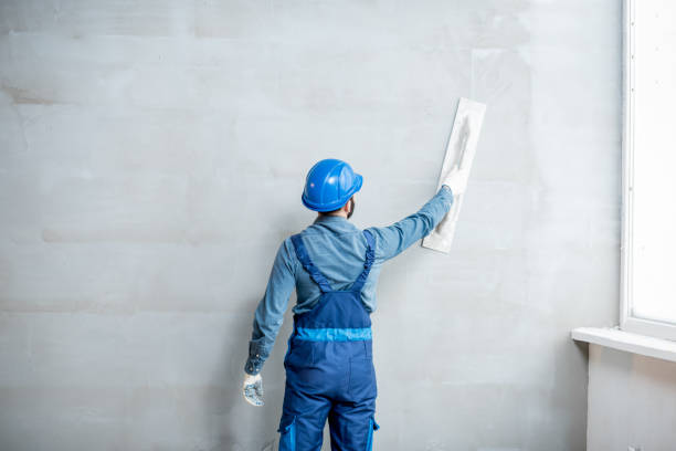 Plasterer working indoors Plasterer in blue working uniform plastering the wall indoors plaster stock pictures, royalty-free photos & images
