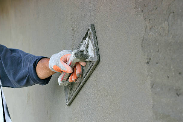 Plastering A Wall Man's hand plastering a wall with trowel. Selective focus. plaster stock pictures, royalty-free photos & images