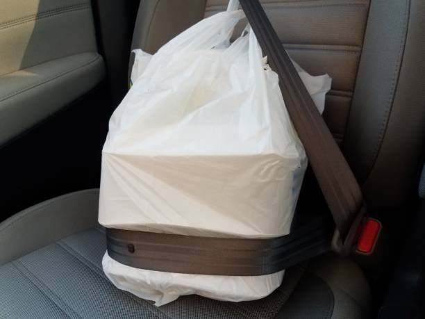 plastic bag with take out or delivery or to go food in seatbelt in car stock photo