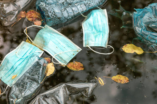 Plastic bottles and face masks polluting river water stock photo