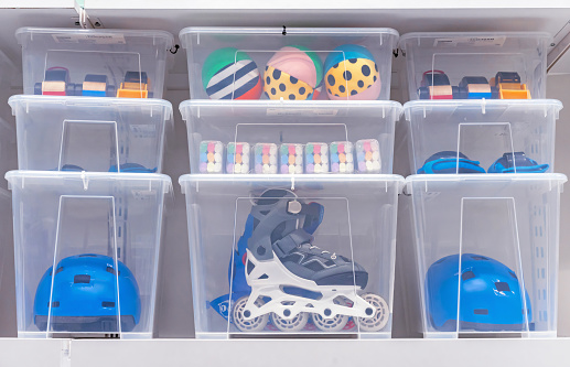 Plastic boxes with children's toys, rollers and a helmet.