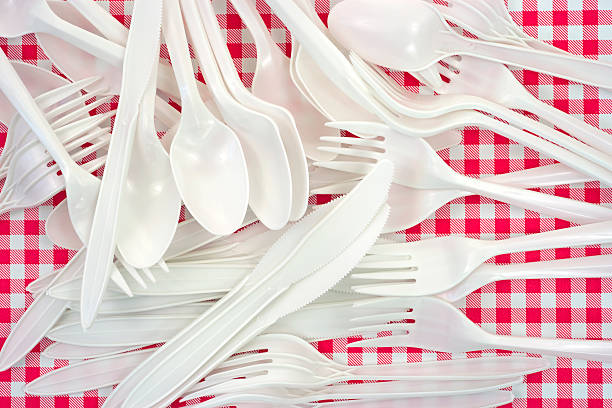 Plastic forks knives spoons A jumble of white plastic forks, knives and spoons on a vinyl checkerboard tablecloth. disposable stock pictures, royalty-free photos & images