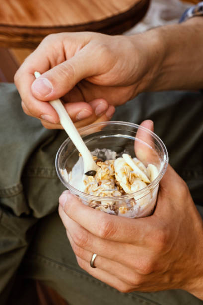 Plastic glass with granola in a man's hand. Summer food in a cafe. Healthy breakfast stock photo