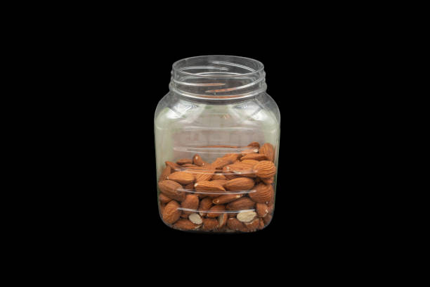 plastic jar with nuts (almonds) on a black background close-up stock photo