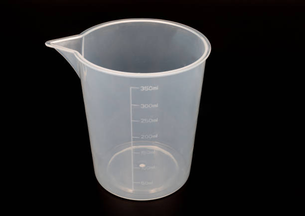 plastic measuring cup on black background close up stock photo