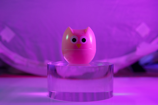 plastic owl toy on the glass cylinder the color background