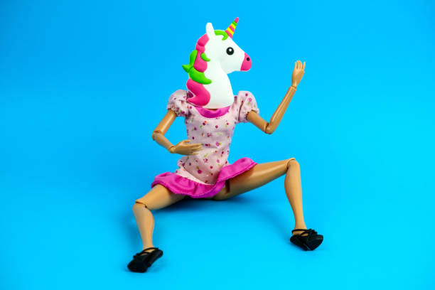 plastic woman doll in pink dress sitting with unicorn mask on her head plastic woman doll in pink dress sitting with unicorn mask on her head isolated on a blue background horse mask photos stock pictures, royalty-free photos & images
