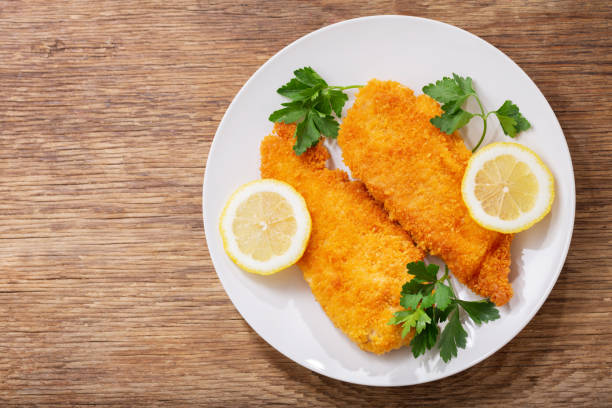plate of chicken schnitzel on a wooden background stock photo