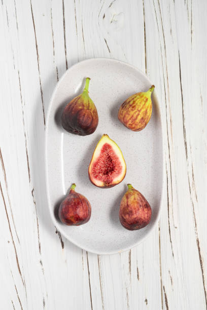 A plate of fresh figs on white wooden background. stock photo