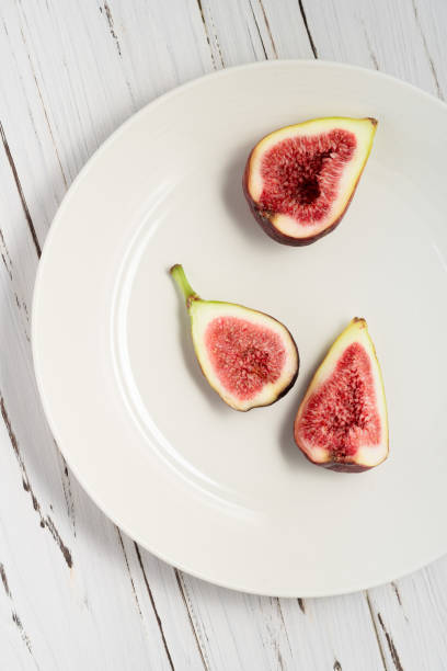 A plate of fresh figs on white wooden background. stock photo