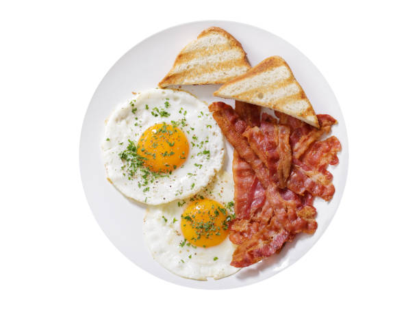 plate of fried eggs, bacon and toast on white background, top view stock photo