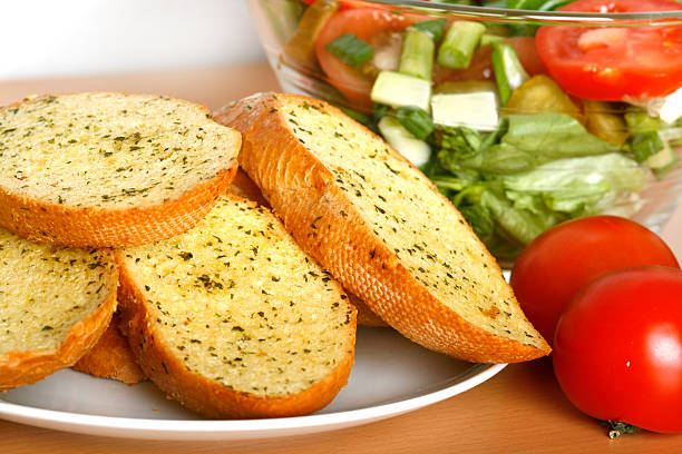 A plate of garlic bread with tomatoes and salad on a table Garlic bread and salad garlic bread stock pictures, royalty-free photos & images