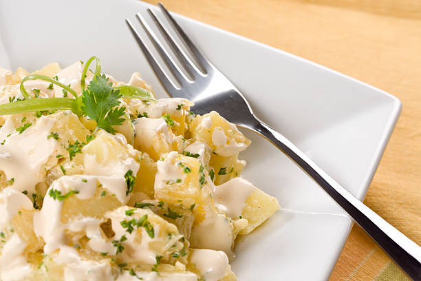 A plate of potato salad with a fork on it  stock photo