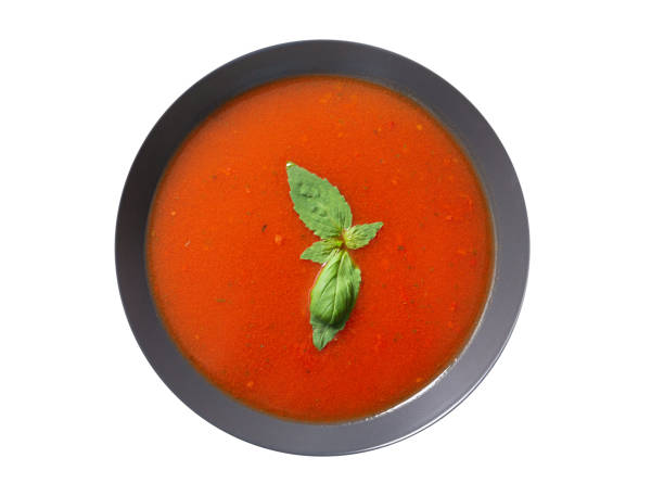 plate of tomato soup with basil isolated on a white background stock photo