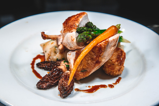 plated chicken roast dinner in restuarant kitchen with gravy morel mushrooms and carrot