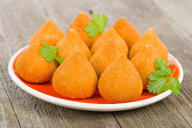 Platter of Coxinha de Galinha delights on a wooden surface Coxinha de Galinha - Brazilian deep fried chicken snack, popular at local parties. Served with chili sauce. savory food stock pictures, royalty-free photos & images