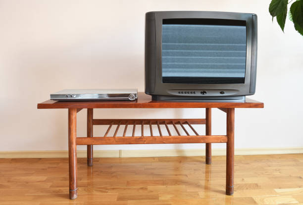 A DVD player and an outdated black TV sit on a vintage table in a 1990s apartment block. A DVD player and an outdated black TV sit on a vintage table in a 1990s apartment block. 90s television set stock pictures, royalty-free photos & images