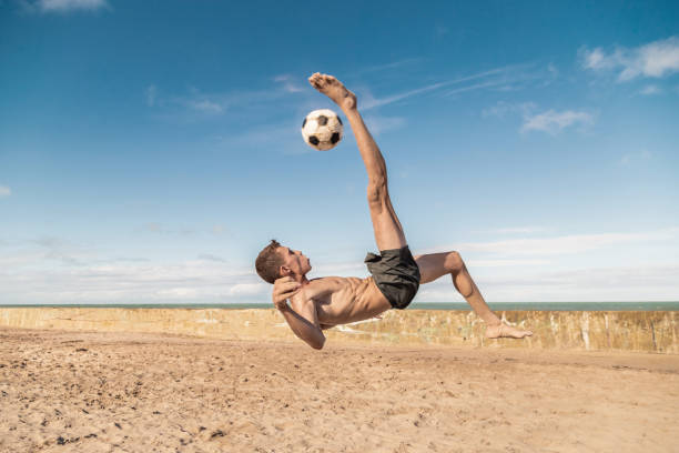 player kicking the ball in the air - futebol de praia imagens e fotografias de stock