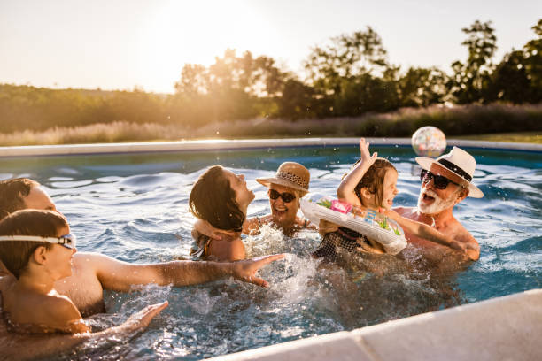 Playful extended family having fun in the swimming pool. stock photo